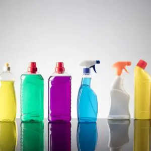 Colorful cleaning bottles on reflective surface.